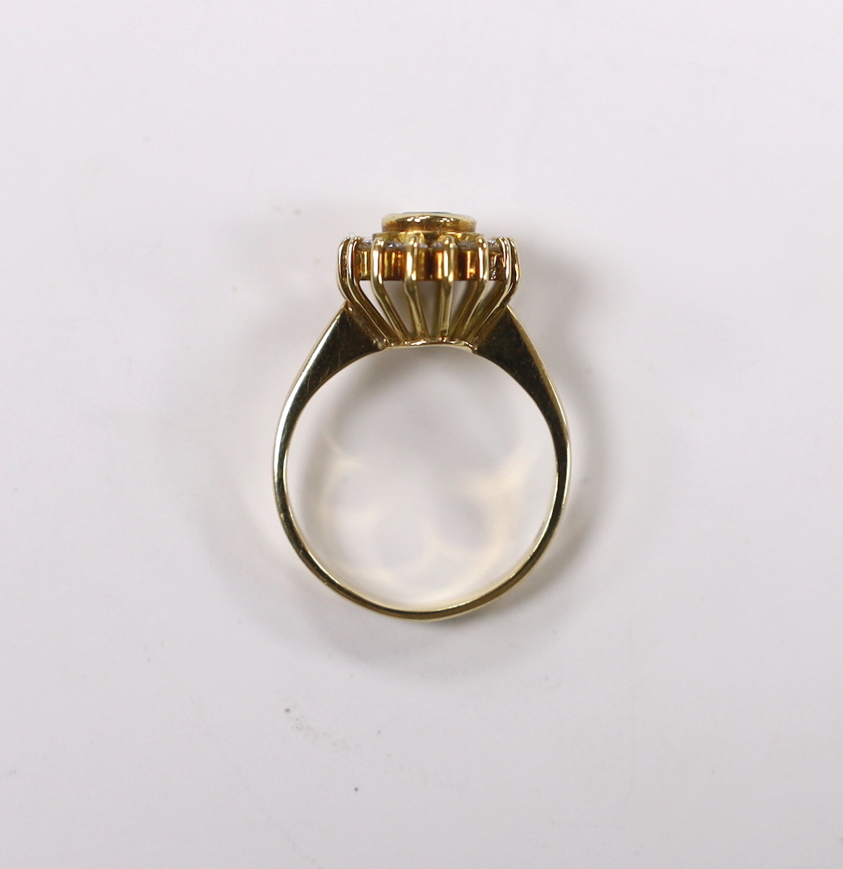 An 18k, emerald and diamond set oval cluster ring, size L, gross weight 5 grams.